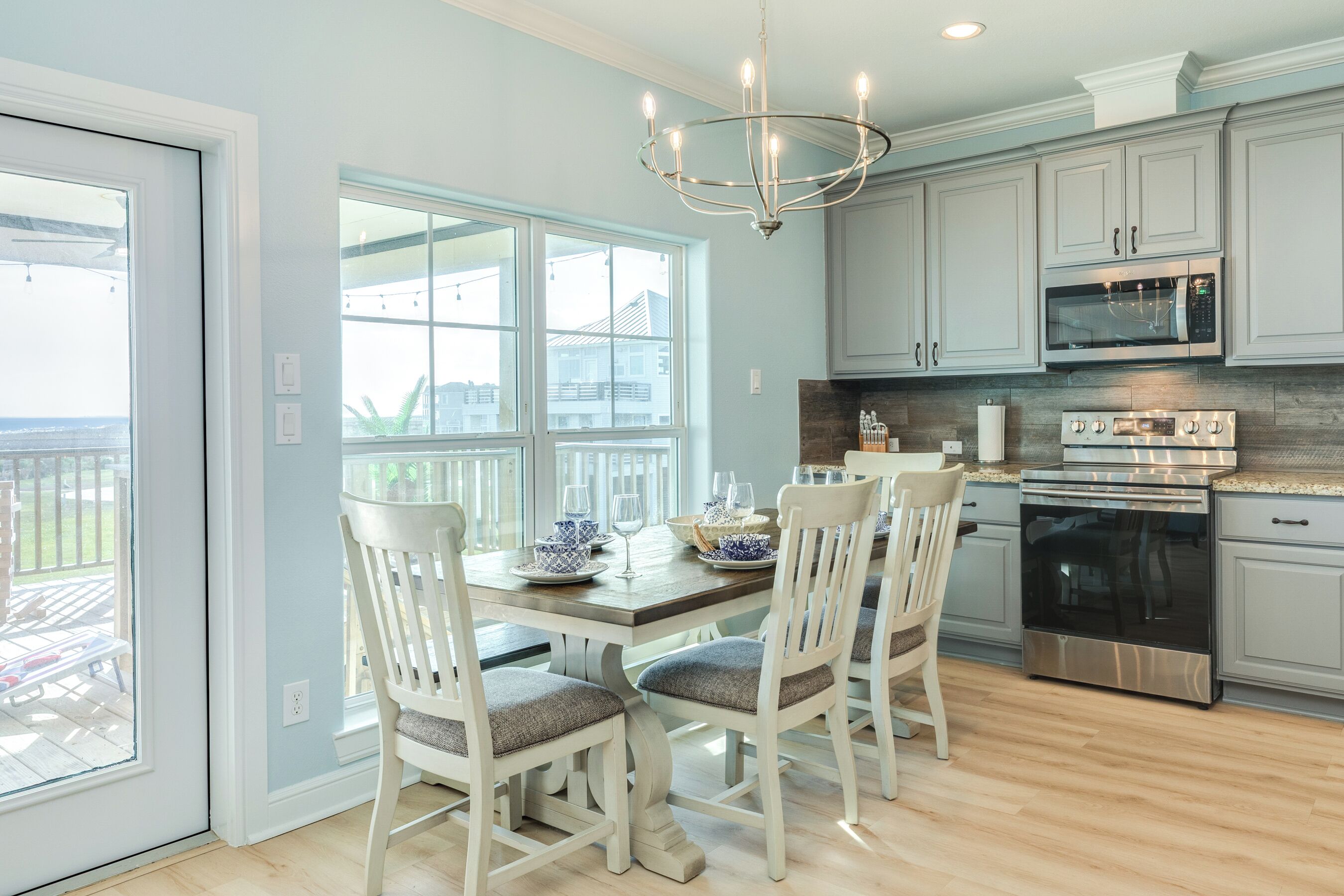 A kitchen with white cabinets, stainless steel appliances, and a dining area with a table and chairs.