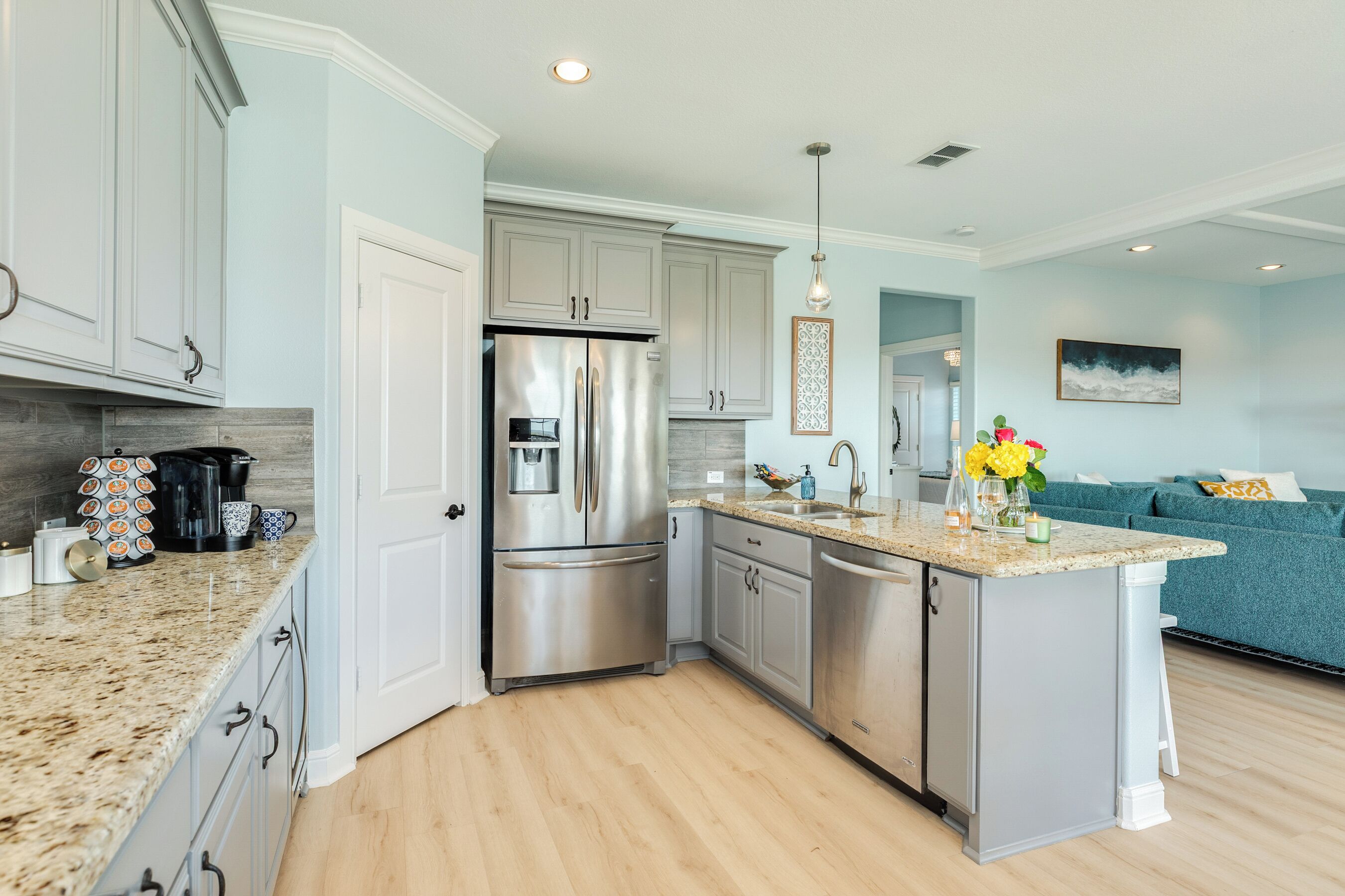 A modern kitchen with stainless steel appliances, granite countertops, and light blue cabinetry.