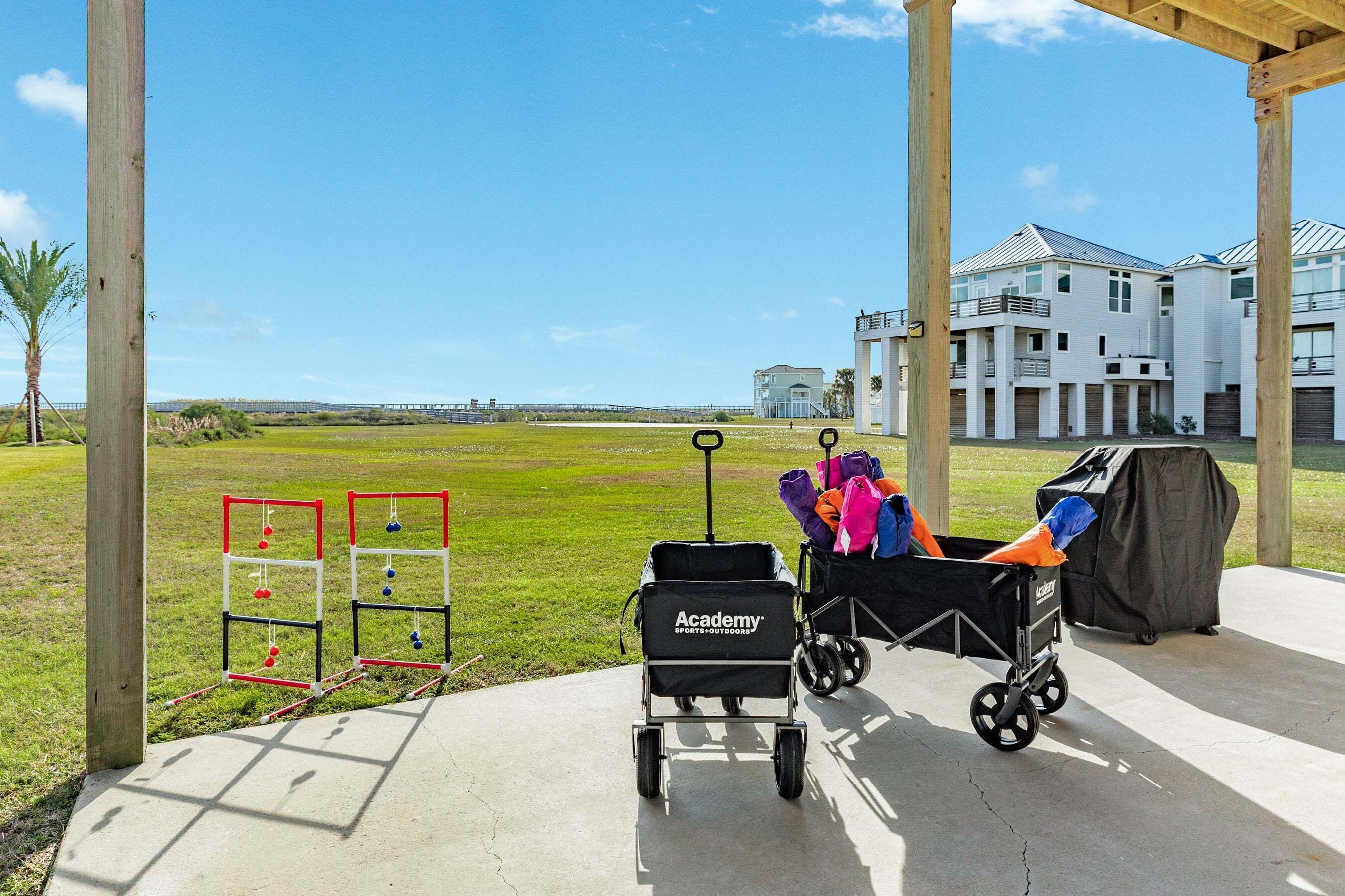 A covered outdoor area with a concrete floor, a golf cart, and a portable grill.