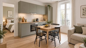 A modern kitchen with grey cabinets, a wooden dining table, and black chairs. - L’Écrin Charléty · Appartement cosy face au stade (Paris)