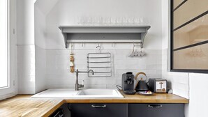 A modern kitchen with a white sink, a coffee maker, a kettle, and a toaster on the counter. - Magnifique duplex avec terrasse et vue imprenable sur la Tour Eiffel (Paris)