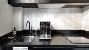 Una cucina moderna con macchina da caffè integrata, lavandino e pensili in acciaio inossidabile.
