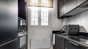 Una cucina moderna con forno integrato, macchina da caffè e una finestra con persiane.