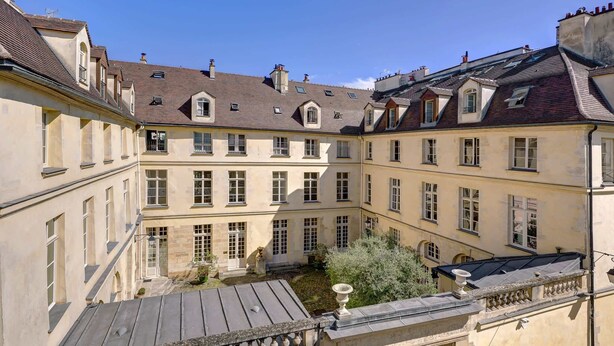 A courtyard with buildings featuring multiple windows and a central fountain. - Studio Parisien avec une vue extraordinaire (Paris)