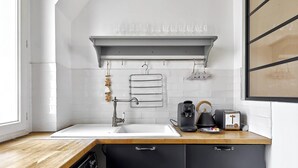 Eine moderne Küche mit einer weißen Spüle, einer Kaffeemaschine, einem Wasserkocher und einem Toaster auf der Arbeitsfläche.