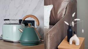 Una tetera eléctrica color turquesa con mango de madera y un tostador moderno sobre una superficie de madera.