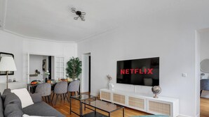 Una sala moderna con una televisión de pantalla plana, un comedor con sillas y un sofá.