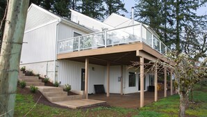 A modern house with a covered porch, a staircase leading to a deck, and a small garden area. - Vineyard 1 bedroom apartment in West Salem - Gorgeous Views. (Salem)