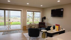 A modern living room with a large window, a flat-screen TV, and a cozy seating area. - Vineyard 1 bedroom apartment in West Salem - Gorgeous Views. (Salem)