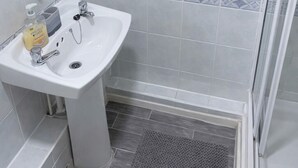 A bathroom with a white sink, a mirror, and a shower area. - Elegant & Family-Friendly Stay | Space, Style & Comfort (Coventry)