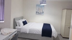 Een slaapkamer met een bed, nachtkastje, kledingkast en een schilderij aan de muur.