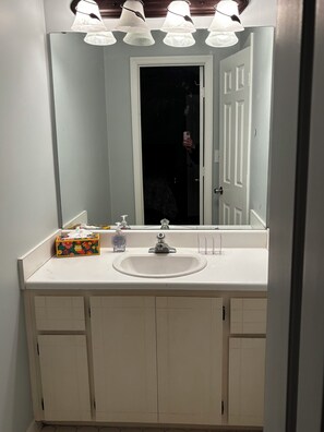 A bathroom with a white sink, a mirror, and a door. There is a box of tissues and a bottle of hand sanitizer on the sink. - 3-bedroom condo in Augusta 4mi from Augusta National (Augusta)