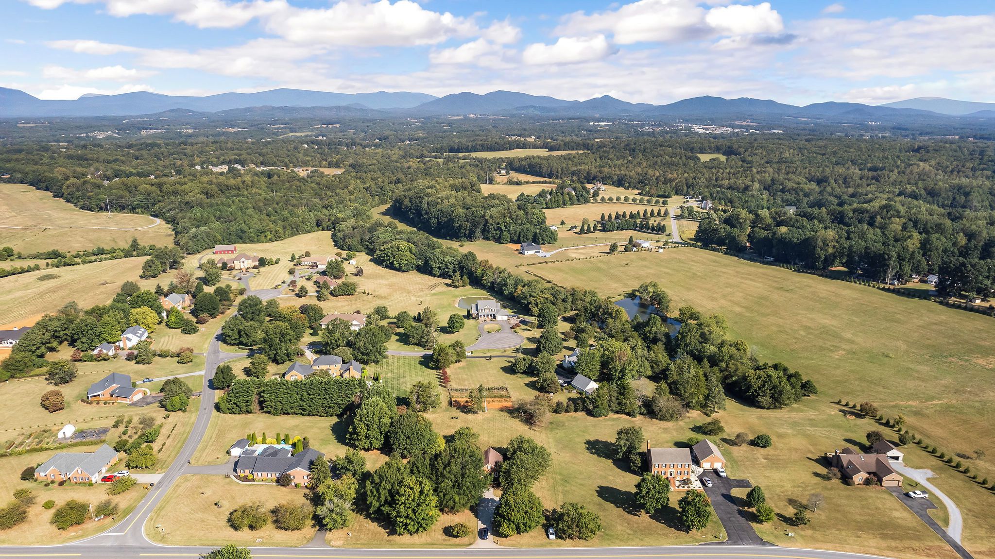 An aerial view of a residential area with houses, roads, and surrounding greenery.