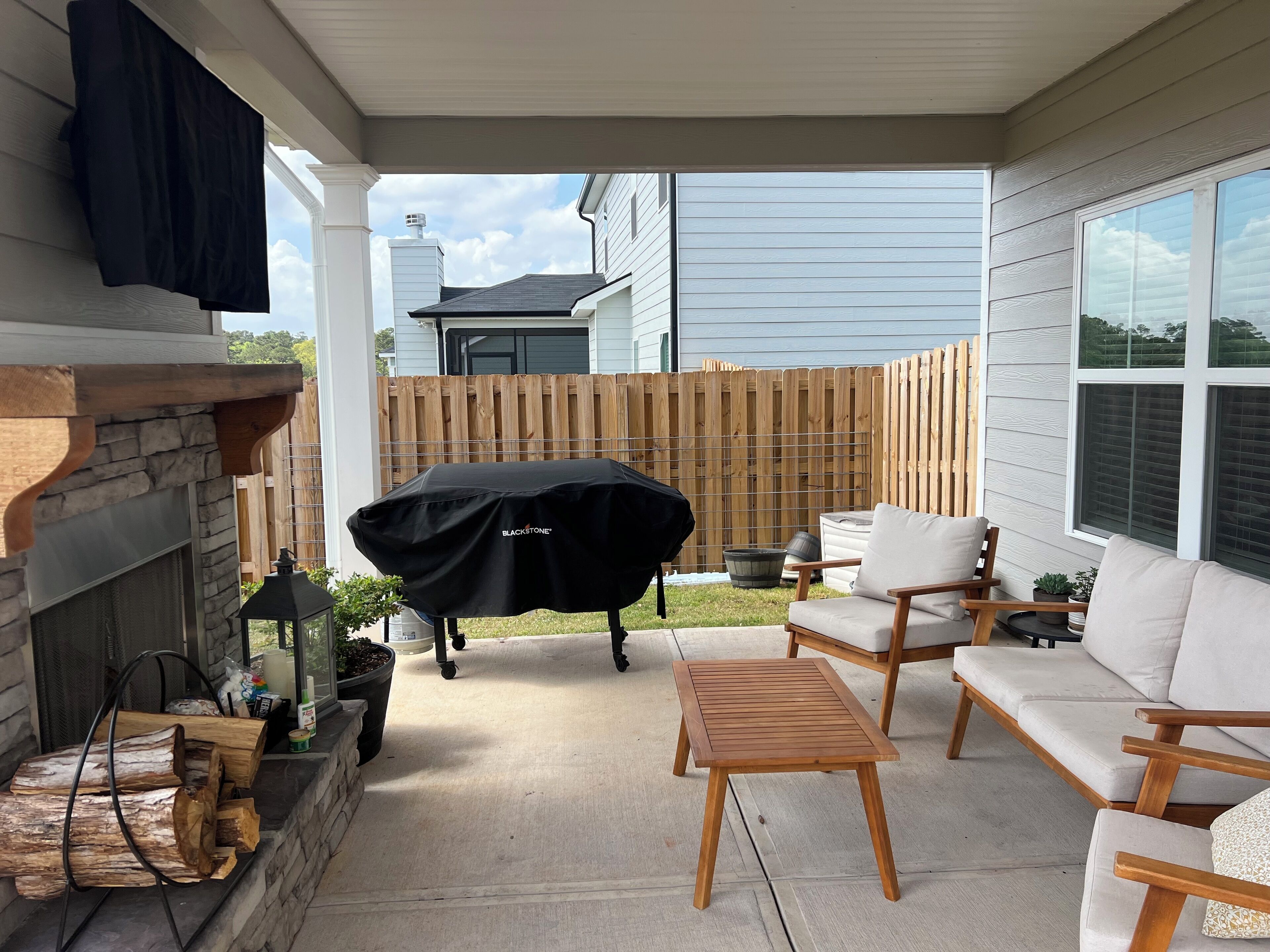 Un patio cubierto con una parrilla, asientos al aire libre y una chimenea de piedra.