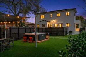 Een modern huis met een achtertuin, terras, barbecueplek en een verzorgd gazon.