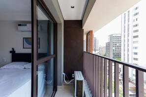 A modern hotel room with a balcony, a bed, a window, and an air conditioning unit. - Studio 402 Perdizes 900m Allianz Parque c Academia (São Paulo)
