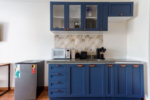 A kitchen with blue cabinets, a microwave, and a refrigerator. - Studio 402 Perdizes 900m Allianz Parque c Academia (São Paulo)