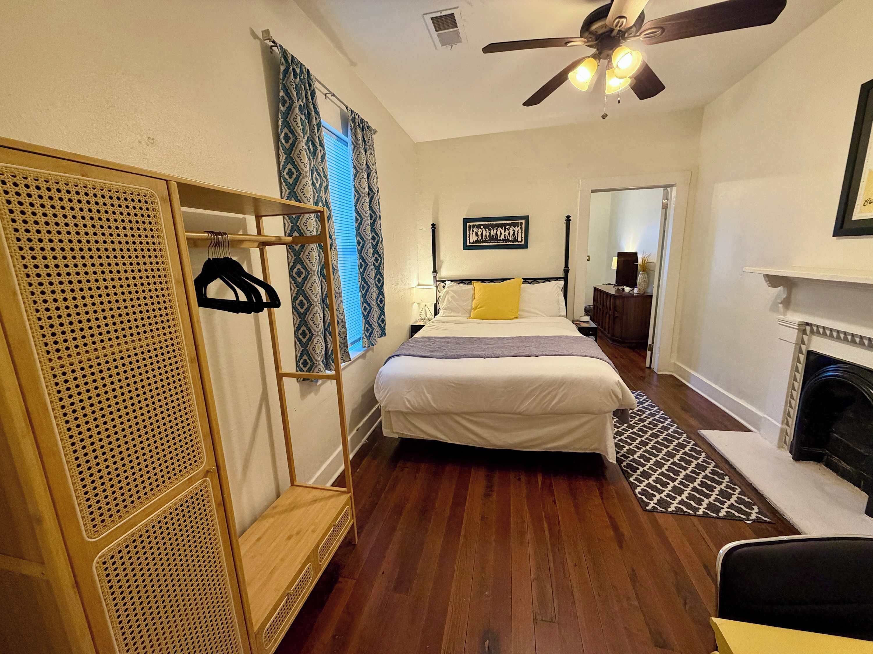 Une chambre à coucher comprenant un lit, une armoire, un ventilateur de plafond, une cheminée et un miroir.