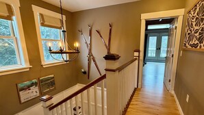 Una escalera de madera con barandillas blancas, un candelabro y luces fijadas en la pared.