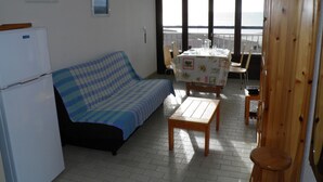 Una sala de estar con sofá, mesa y vistas al mar a través de amplios ventanales.