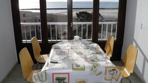 Mesa de comedor dispuesta para seis personas con vista al mar a través de amplias ventanas.