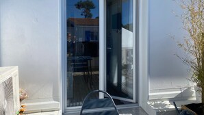 Porta a vetri scorrevoli che dà accesso a un'area esterna con una sedia, una ventola e una pianta in vaso.