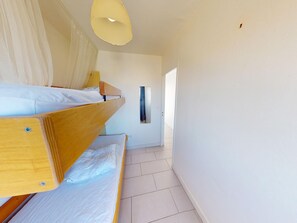 A room with two bunk beds, a small window, and a plain white wall. - T2 Apartment in Frontignan-Plage with Terrace and Parking (Frontignan)