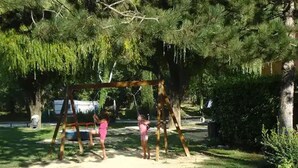 A swing set in a park with trees and a grassy area. - Spacious mobile home - 8 guests (Visan)