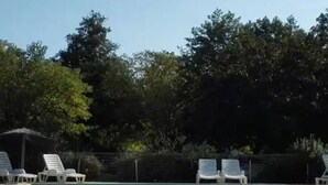 Ein Schwimmbad mit weißen Liegestühlen und einem Zaun.