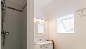 Ein Badezimmer mit Dusche, Waschbecken und Fenster.