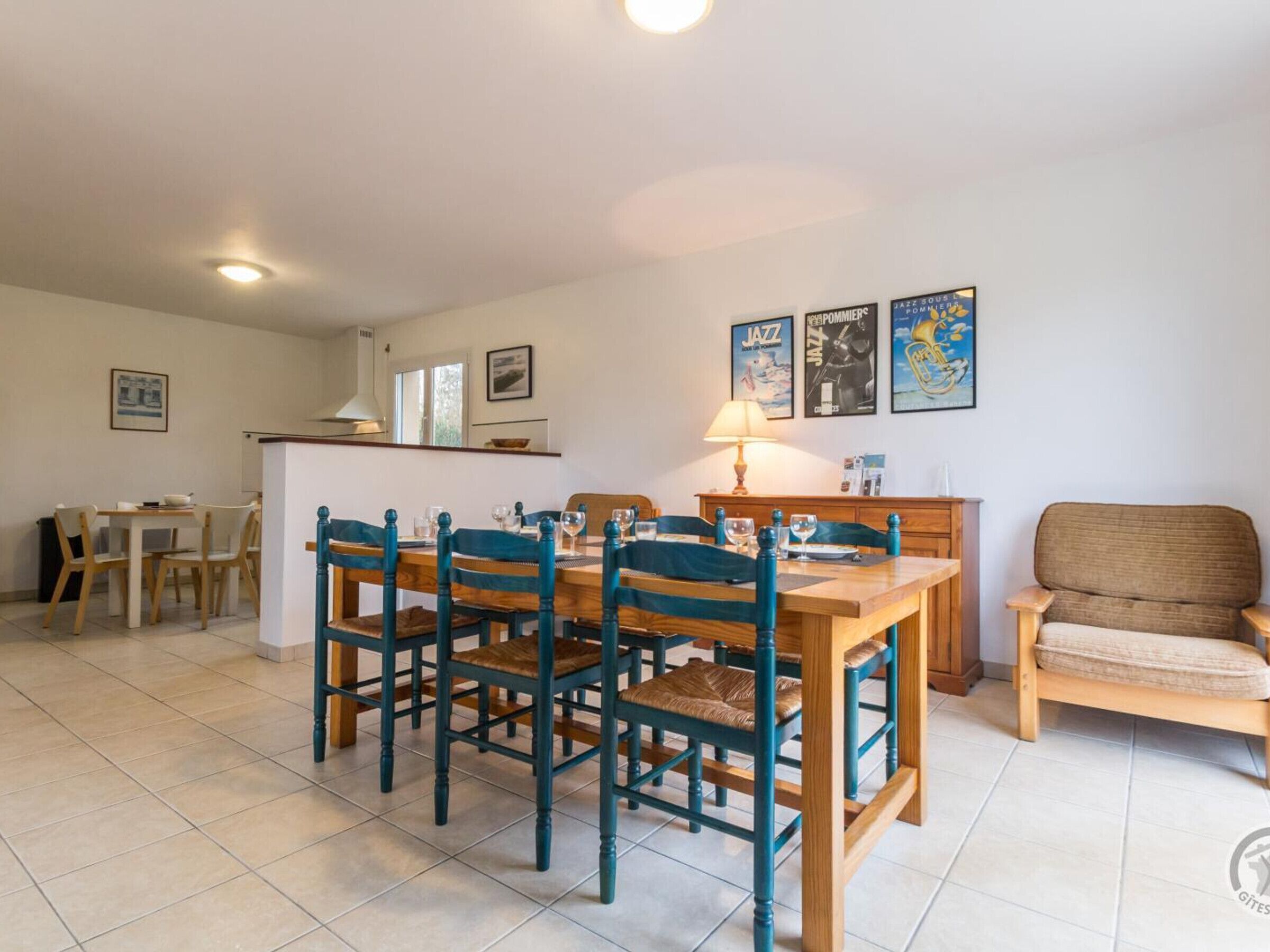 A dining area with a wooden table and chairs, a kitchen area with a counter and sink, and a seating area with a chair.