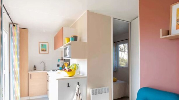 Een compacte woonruimte met een kitchenette, een eethoek en een slaapbank.