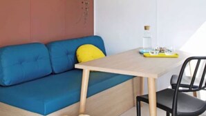 Een kamer met een blauwe bank, een houten tafel en een zwarte stoel.