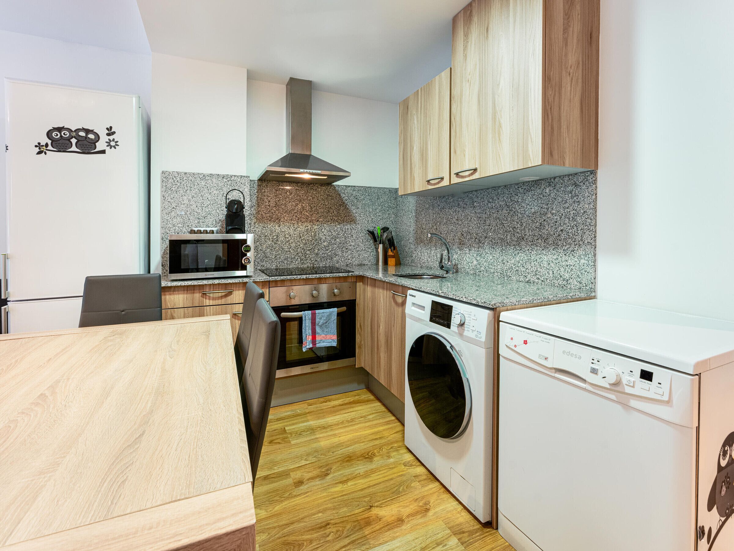 A compact kitchen with a microwave, oven, washing machine, and a sink.