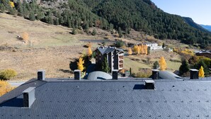 Un paisaje montañoso con un edificio de techo inclinado y varias chimeneas.