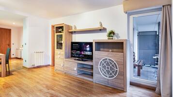A modern living room with a wooden entertainment unit, a television, and a sliding glass door leading to an outdoor area.