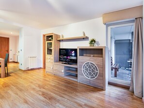Moderni olohuone, jossa on puinen mediakeskus, televisio ja liukuovet, jotka johtavat ulkotilalle.