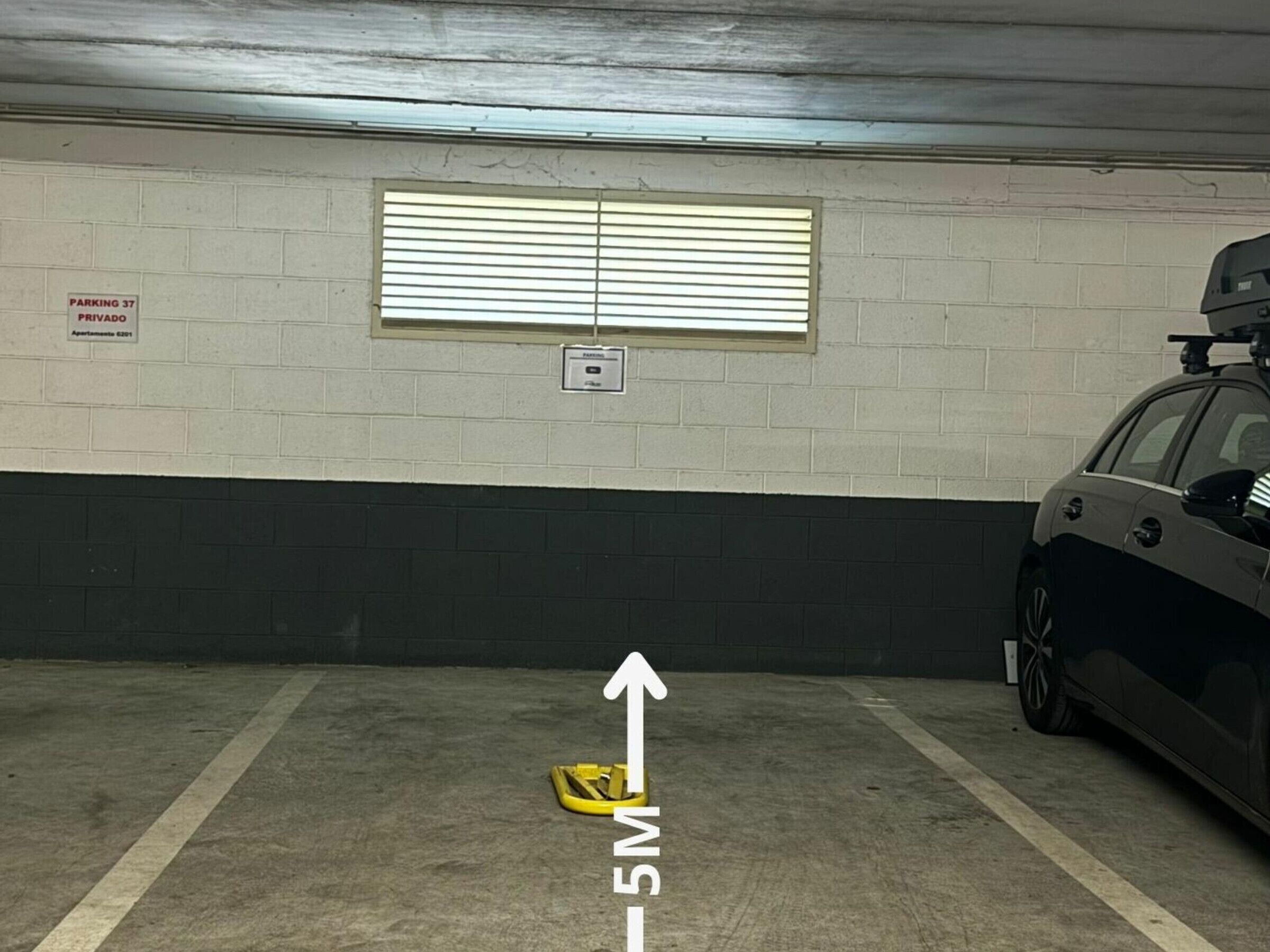 A parking garage with a car parked in a spot marked with an arrow indicating the direction to the exit.