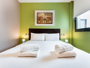 Een hotelkamer met een bed, twee bedlampen, een schilderij aan de muur en een raam.
