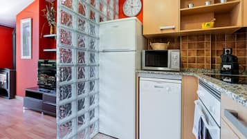 Eine kleine Küche mit Kühlschrank, Mikrowelle und Backofen.