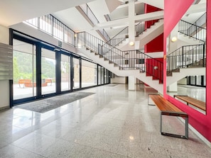 A spacious interior with a central staircase, large windows, and a red accent wall. - Cozy 3-Bedroom Apartment in Arinsal with Parking (Arinsal)