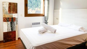 Ett hotellrum med en säng, ett fönster med utsikt över träd, ett element och en tavla på väggen.