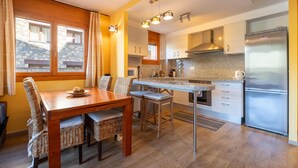 Una cocina moderna con una mesa de comedor, sillas y un refrigerador empotrado.