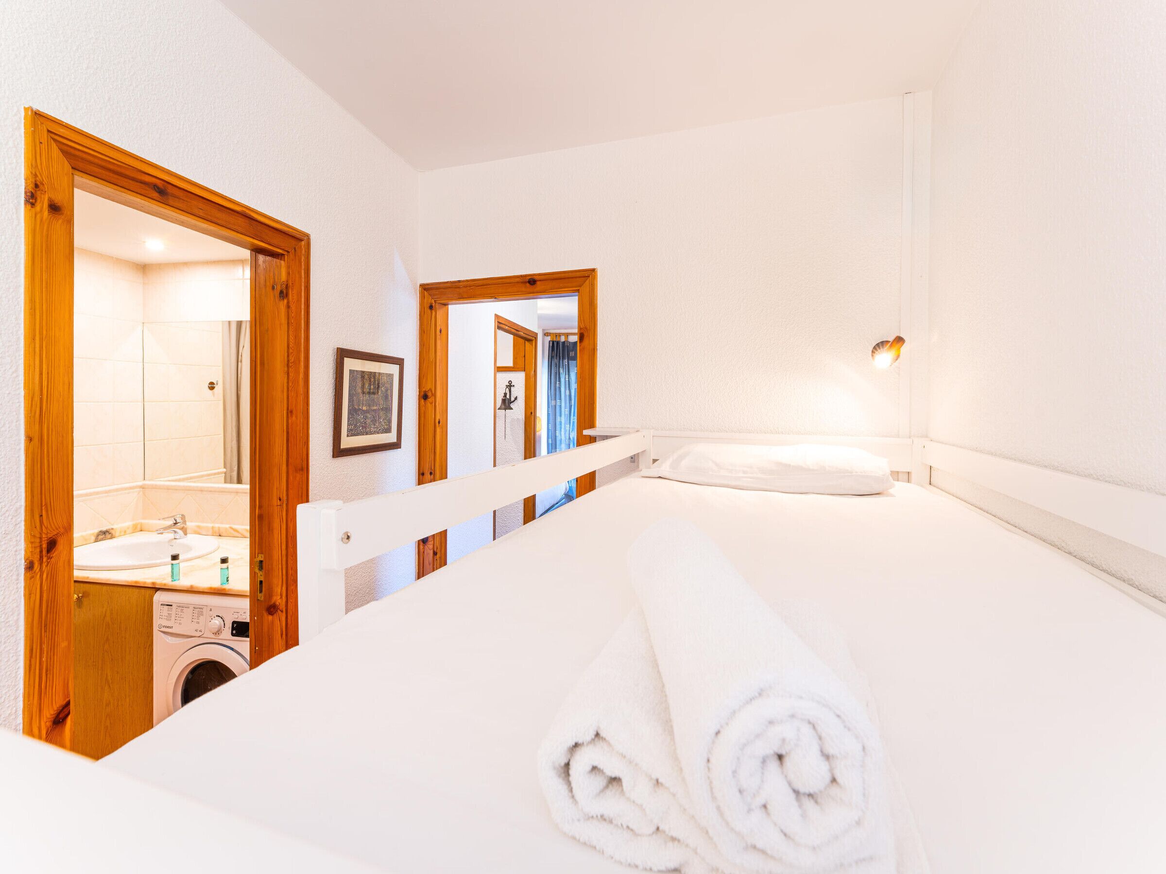 Habitación de hotel con cama, lavadora, espejo y baño con lavamanos y ducha.