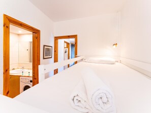 Habitació d'hotel amb llit, rentadora, mirall i bany amb vàter i dutxa.