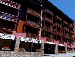 A multi-story building with balconies, stone walls, and flower boxes. - Panoramic Studio in El Tarter with Parking - 4 pax (El Tarter)