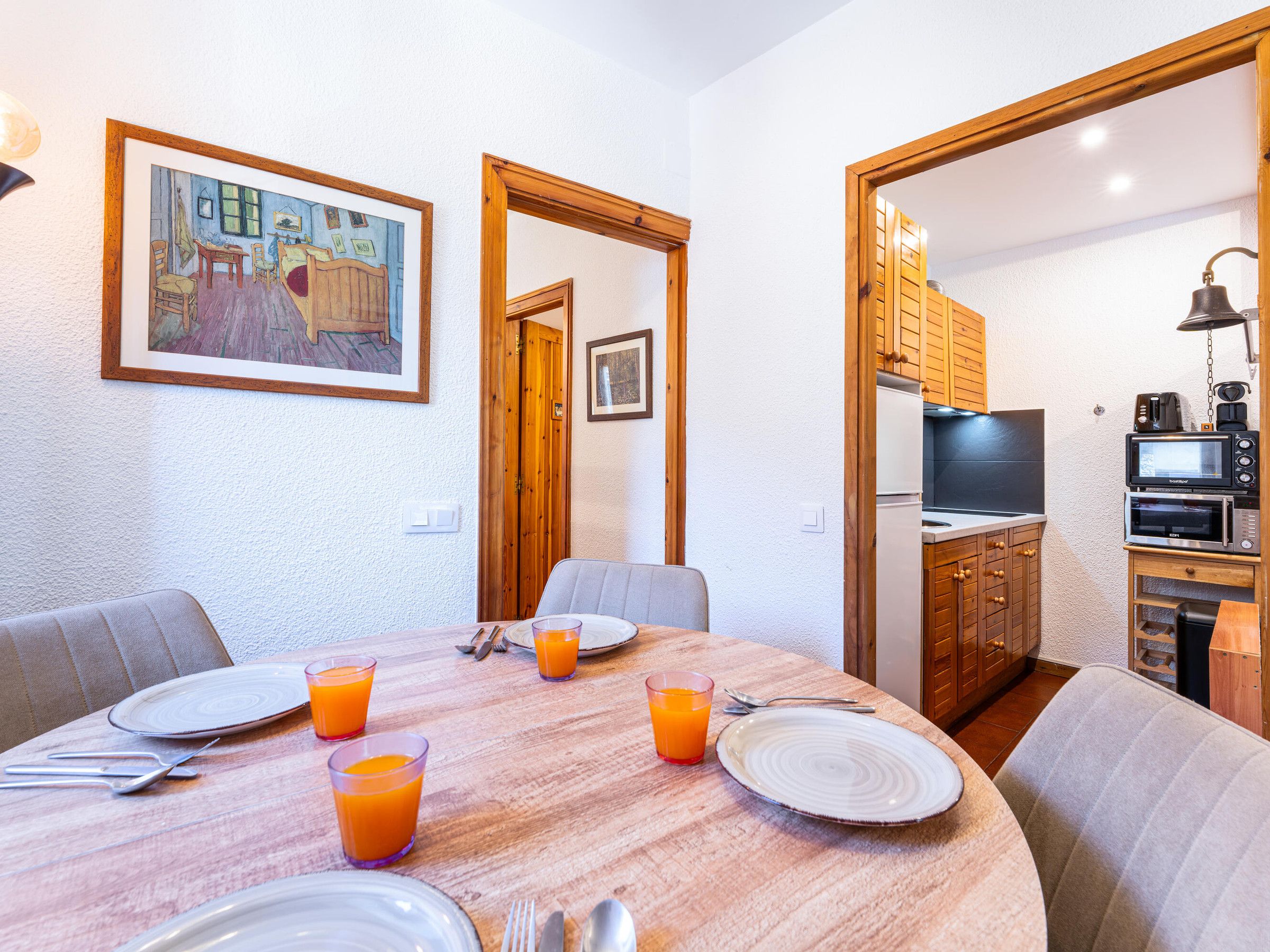 A dining area with a wooden table, chairs, and a painting on the wall.