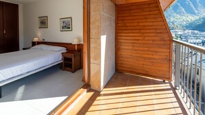 A bedroom with a bed, bedside tables, and a view of a city and mountains.