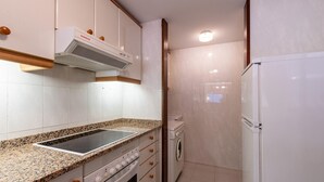 A compact kitchen with a built-in stove, oven, and microwave, a washing machine, and a refrigerator.