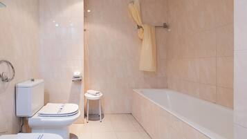 A bathroom with a toilet, bidet, and bathtub.